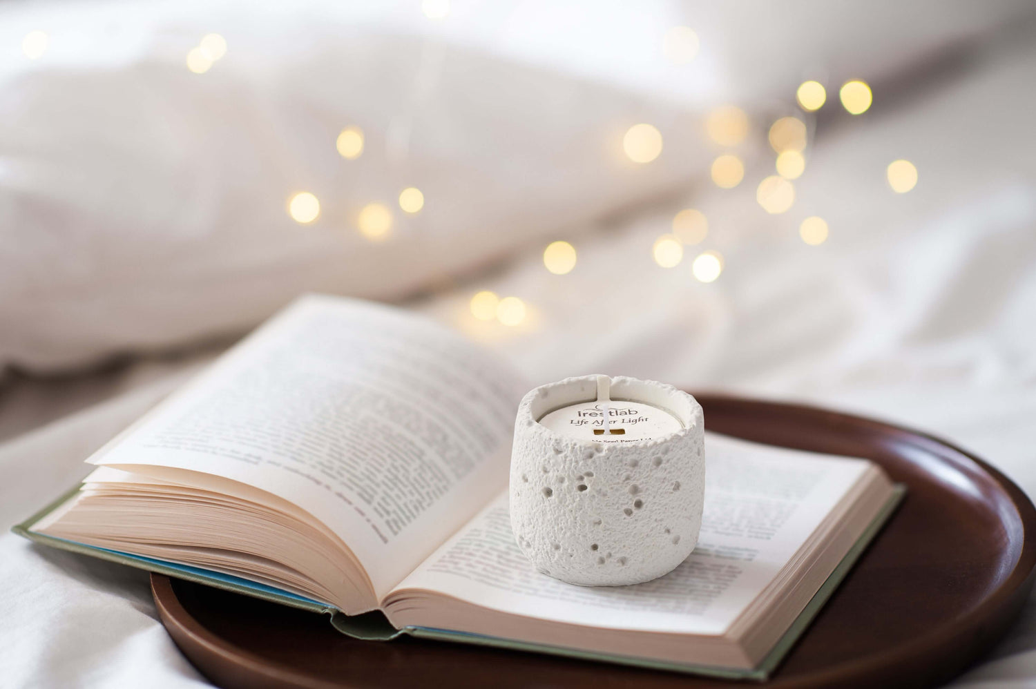A cozy scene with a candle on an open book, surrounded by soft warm lights, perfect for relaxation and meditation.