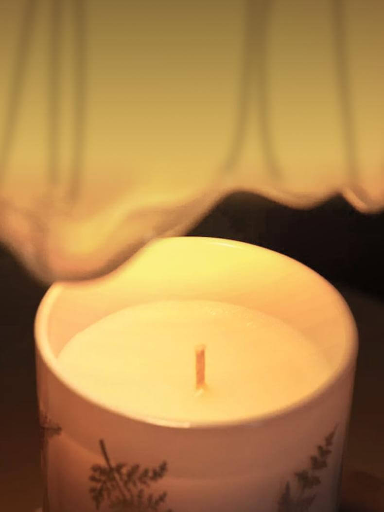 Scented wax warmer lamp illuminating a decorative candle with a warm glow, enhancing ambiance and fragrance.