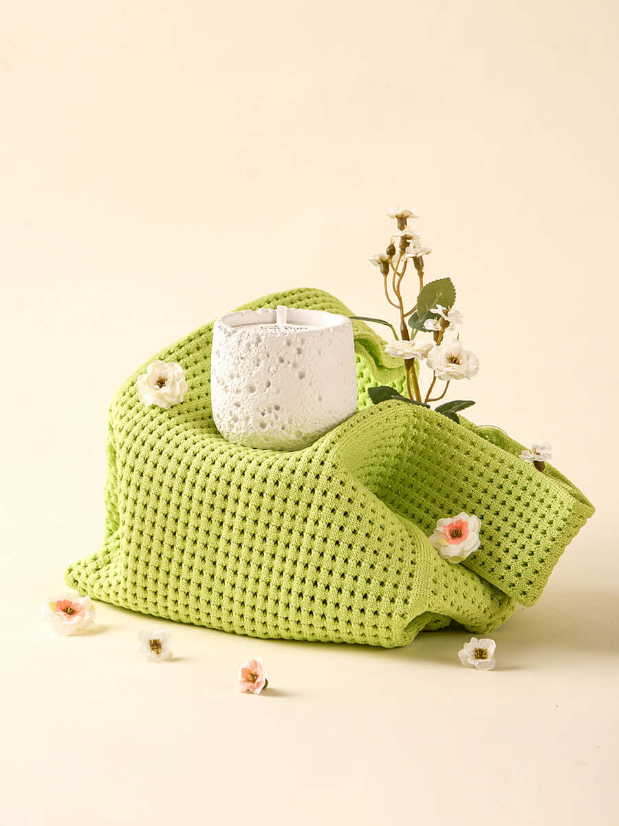 Sustainable irestlab Seed Candle surrounded by delicate flowers and a green fabric, symbolizing mindful living.