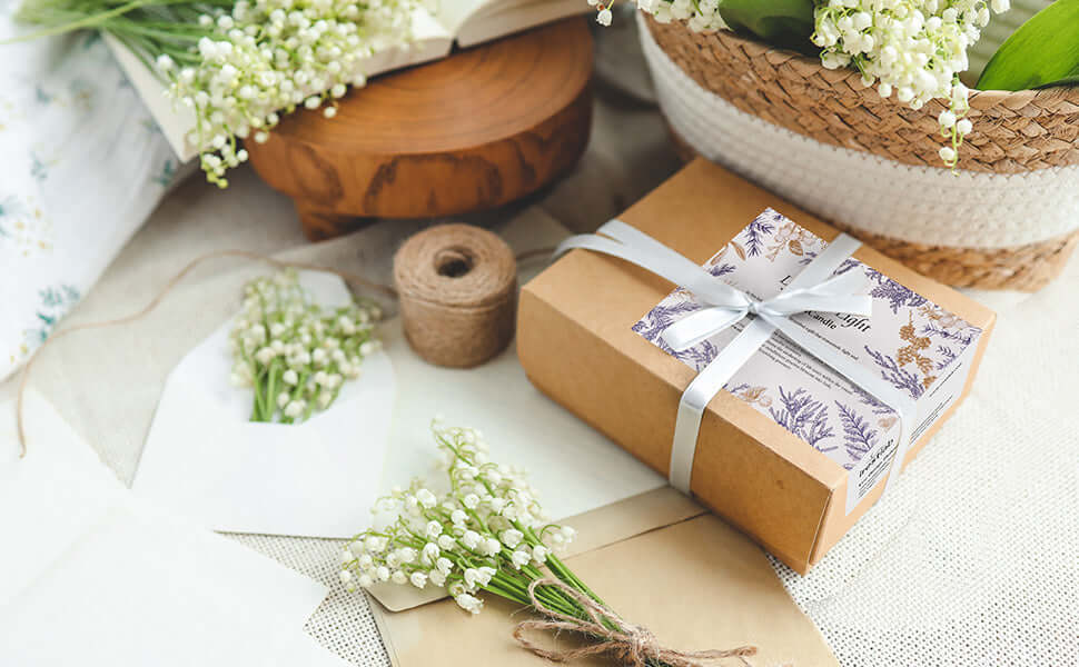 A beautifully wrapped gift box with a floral design, surrounded by fresh flowers and natural decor items.